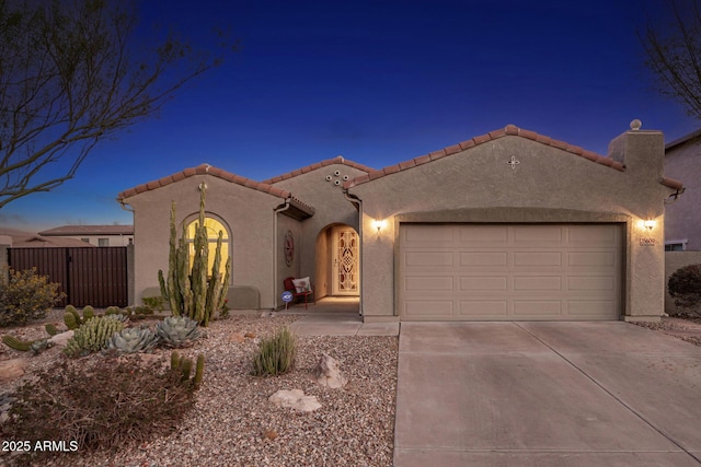 mediterranean / spanish house with concrete driveway, an attached garage, a tile roof, and stucco siding