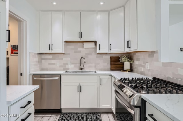 kitchen featuring stainless steel appliances, white cabinetry, and sink