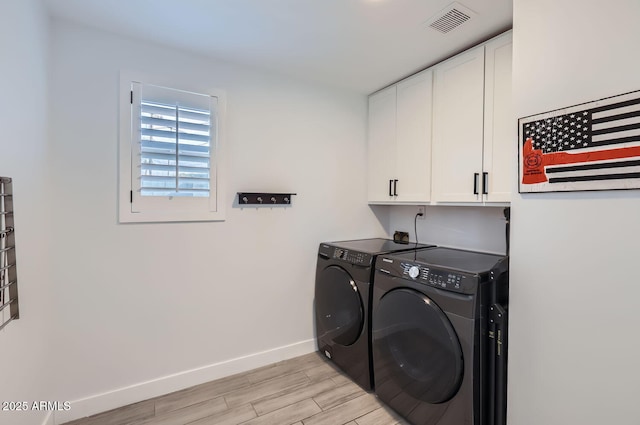 laundry area with washer and dryer, cabinets, and light wood-type flooring