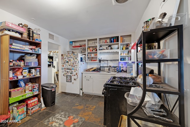 kitchen with white refrigerator, white cabinets, and black gas range oven