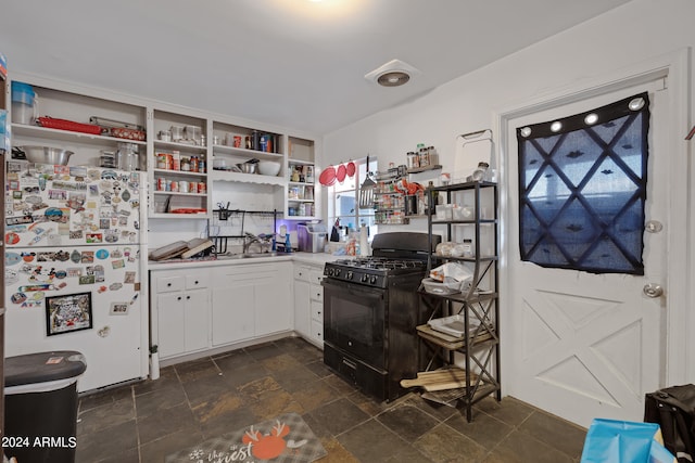 kitchen featuring white fridge, black gas range, and white cabinetry