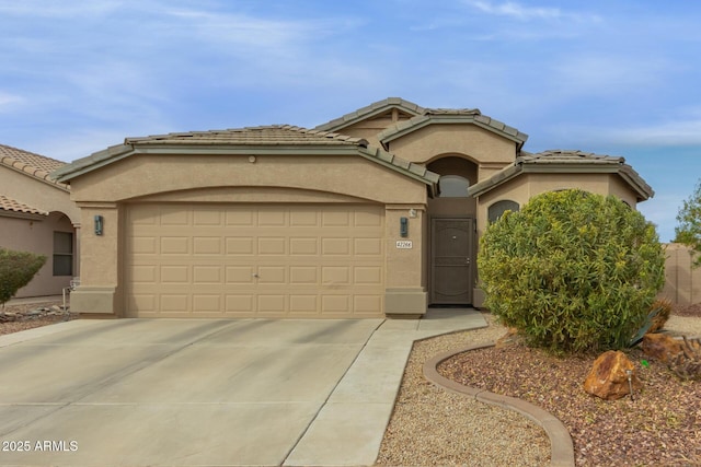 view of front of property with driveway, an attached garage, a tiled roof, and stucco siding