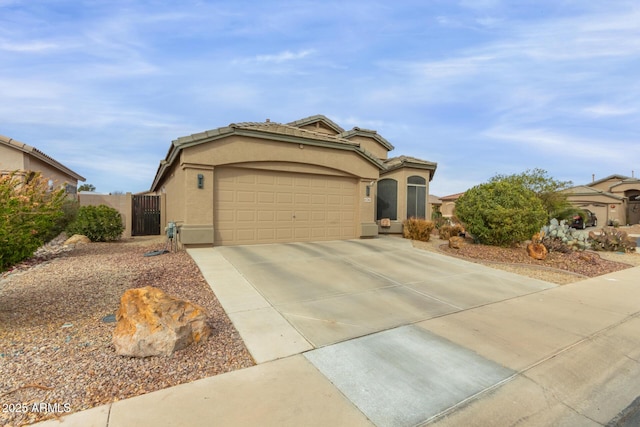 mediterranean / spanish-style house featuring driveway, a garage, a tiled roof, a gate, and stucco siding