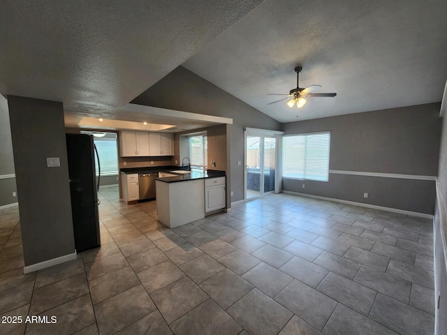 kitchen featuring black fridge, stainless steel dishwasher, vaulted ceiling, sink, and white cabinetry