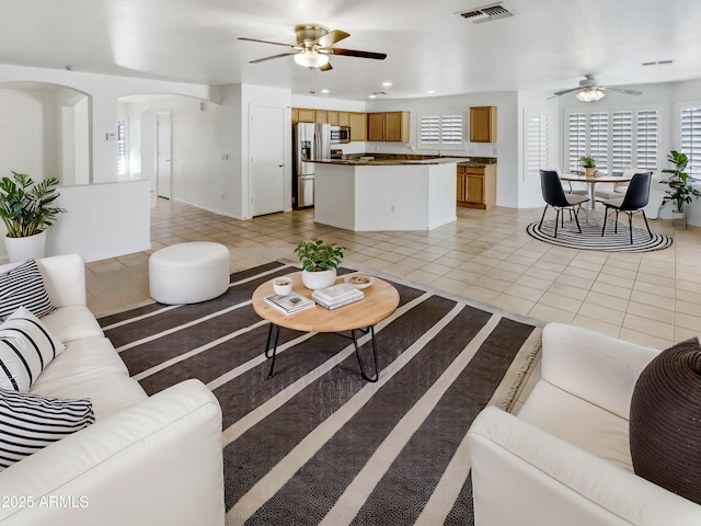 living area with light tile patterned floors, visible vents, arched walkways, a ceiling fan, and recessed lighting