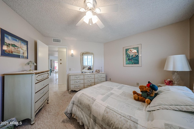 bedroom with ceiling fan, light carpet, and a textured ceiling