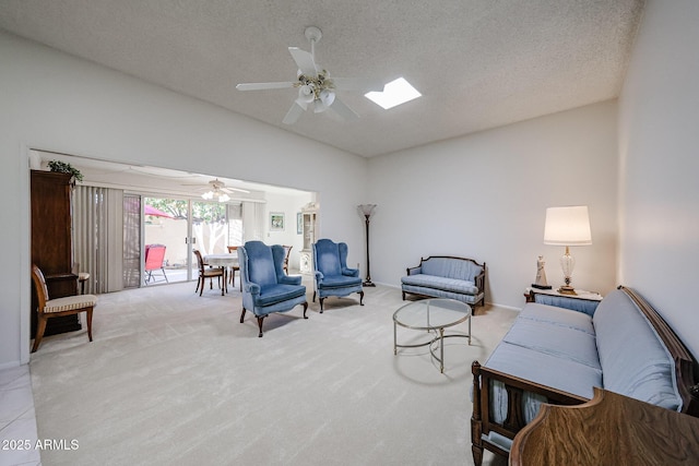 living room with ceiling fan, light colored carpet, lofted ceiling with skylight, and a textured ceiling