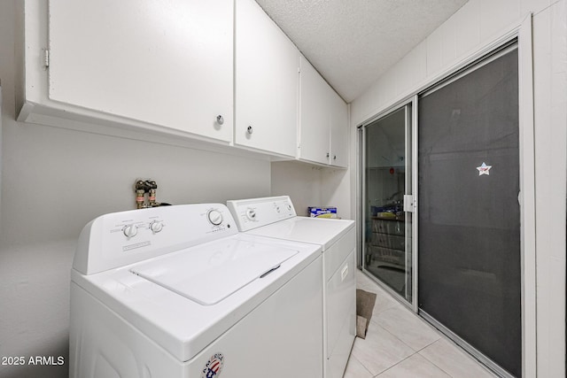 clothes washing area featuring cabinets, washing machine and dryer, a textured ceiling, and light tile patterned floors