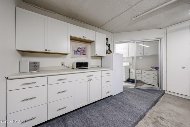 kitchen with washer / dryer, white cabinets, and concrete floors