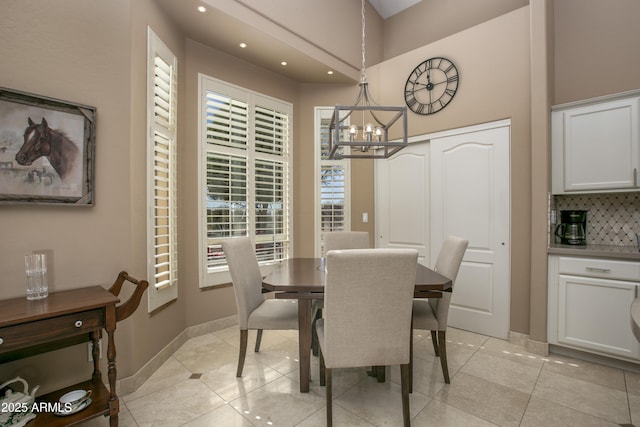 tiled dining room featuring a towering ceiling and a notable chandelier