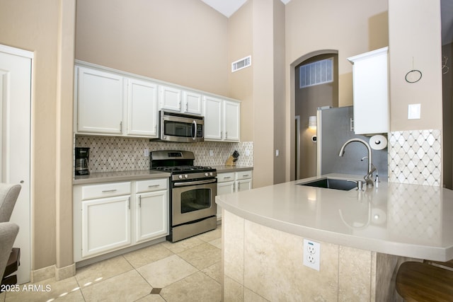 kitchen with sink, stainless steel appliances, white cabinets, light tile patterned flooring, and kitchen peninsula