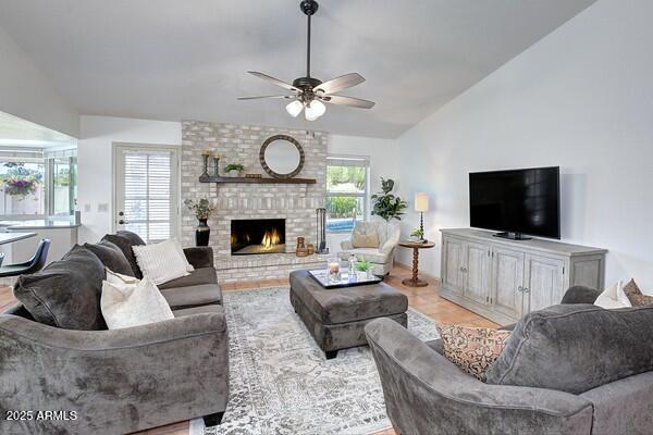 living room featuring ceiling fan, lofted ceiling, and a fireplace