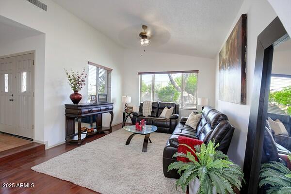 living room with dark hardwood / wood-style flooring, vaulted ceiling, and a wealth of natural light