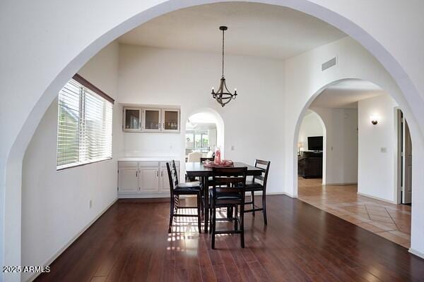 dining room featuring a towering ceiling and dark hardwood / wood-style floors