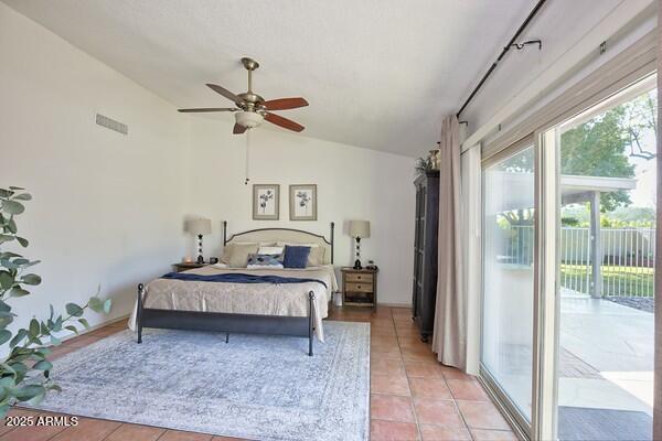 bedroom with rail lighting, ceiling fan, vaulted ceiling, light tile patterned flooring, and access to outside