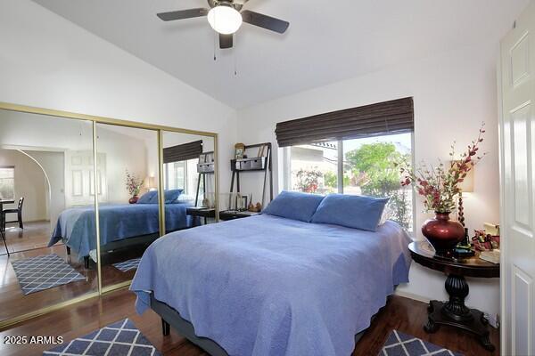 bedroom with lofted ceiling, a closet, dark hardwood / wood-style floors, and ceiling fan