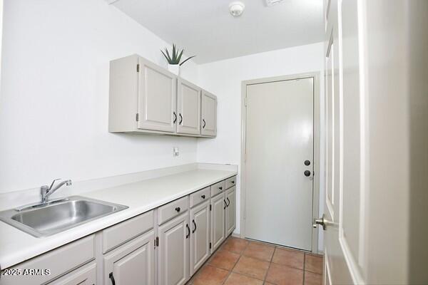 kitchen with gray cabinets, sink, and light tile patterned floors