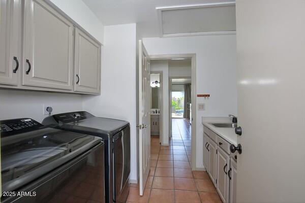 laundry room with cabinets, light tile patterned flooring, washer and dryer, and sink