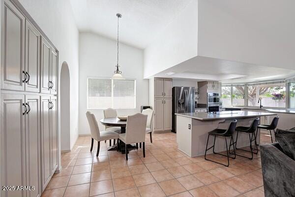 kitchen featuring pendant lighting, appliances with stainless steel finishes, a kitchen bar, and gray cabinets