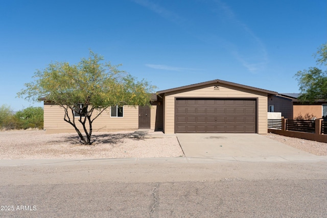 ranch-style house featuring concrete driveway, fence, and a garage