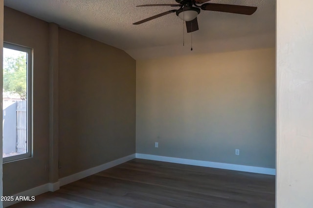 spare room featuring a textured ceiling, dark wood-style flooring, baseboards, lofted ceiling, and ceiling fan