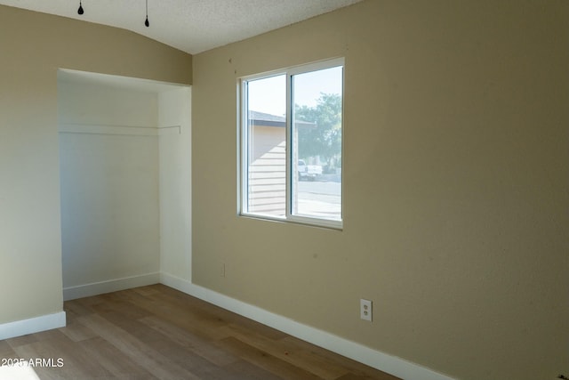unfurnished room featuring baseboards, wood finished floors, and a textured ceiling