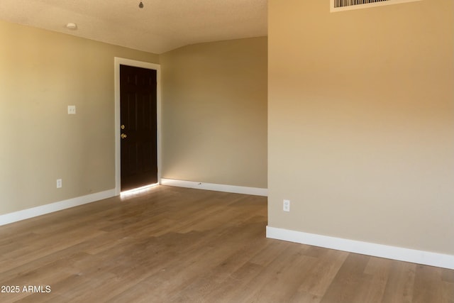 spare room featuring baseboards, wood finished floors, and a textured ceiling
