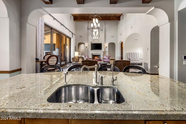 kitchen with beamed ceiling, sink, and stone countertops