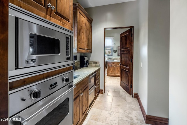 kitchen with stainless steel appliances, light stone countertops, and light tile floors