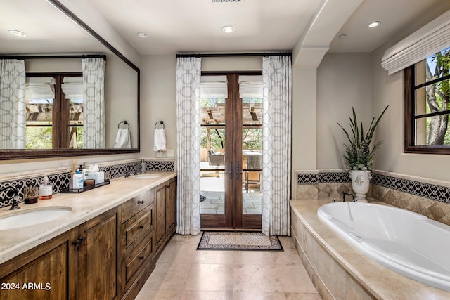 bathroom with plenty of natural light, oversized vanity, double sink, and tiled bath