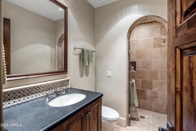 bathroom with toilet, tile flooring, tasteful backsplash, vanity, and tiled shower