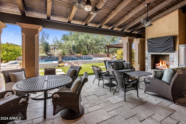 view of patio / terrace with ceiling fan and an outdoor living space with a fireplace