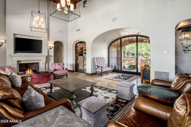 tiled living room featuring a towering ceiling, a chandelier, and a premium fireplace