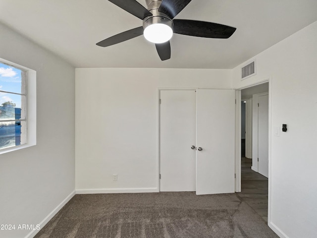 unfurnished bedroom featuring a closet, dark carpet, and ceiling fan