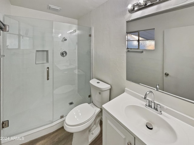 bathroom featuring walk in shower, hardwood / wood-style floors, vanity, and toilet