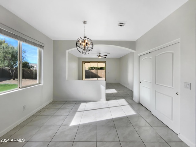 unfurnished dining area featuring plenty of natural light, light tile patterned floors, and ceiling fan with notable chandelier