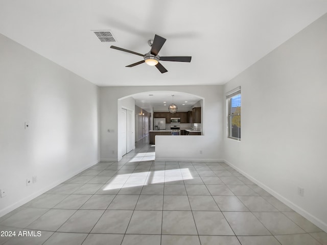 unfurnished living room featuring ceiling fan with notable chandelier and light tile patterned floors