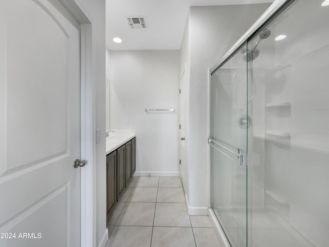 bathroom with tile patterned floors, a shower with door, and vanity