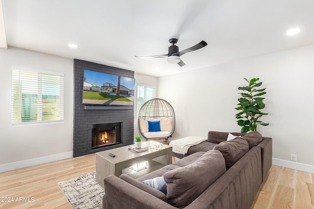 living room with a fireplace, light hardwood / wood-style flooring, and ceiling fan