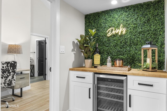 bar featuring white cabinetry, wooden counters, beverage cooler, and light wood-type flooring