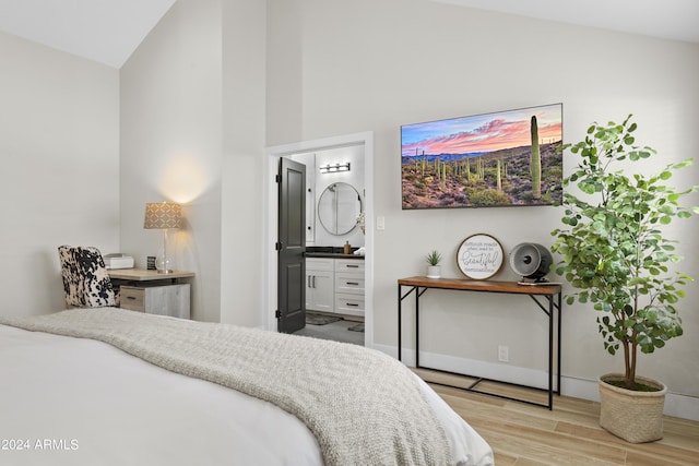 bedroom featuring lofted ceiling, connected bathroom, and light hardwood / wood-style flooring