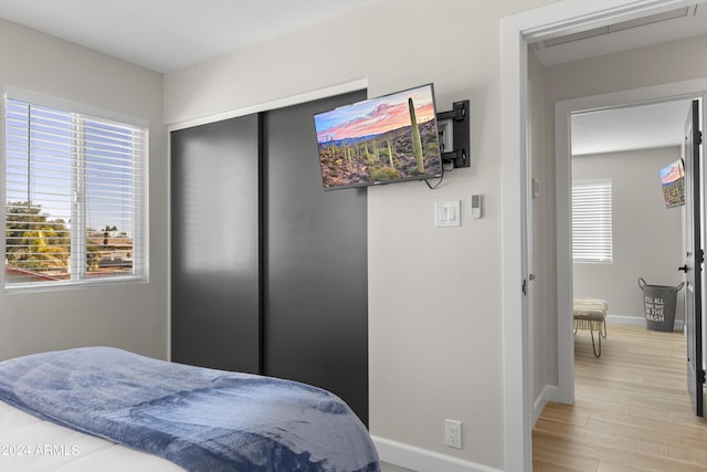 bedroom with light hardwood / wood-style floors and multiple windows