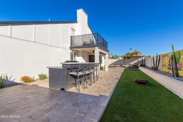 view of yard featuring a patio area, a balcony, and a bar