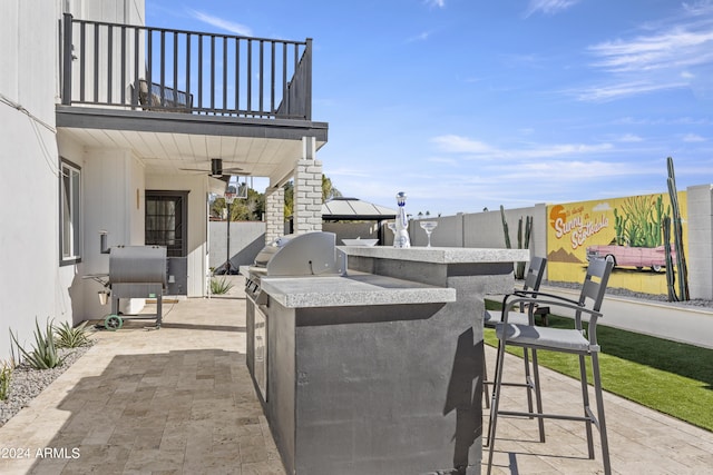 view of patio with grilling area, an outdoor bar, ceiling fan, a balcony, and area for grilling