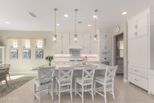 kitchen featuring a center island with sink, white cabinets, and white appliances