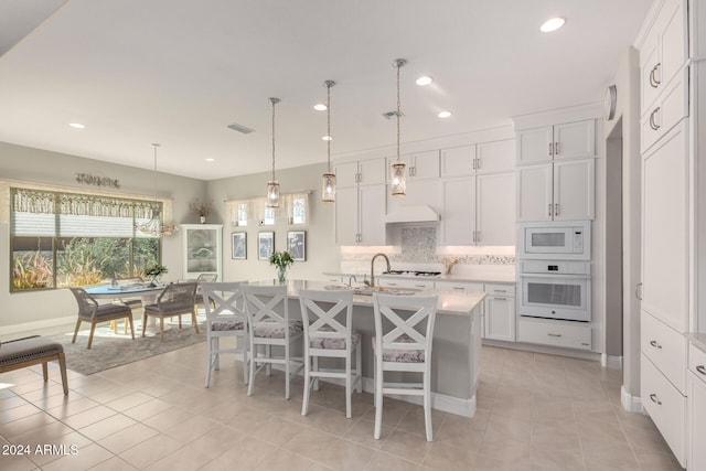 kitchen featuring white cabinetry, white appliances, an island with sink, and light tile patterned floors