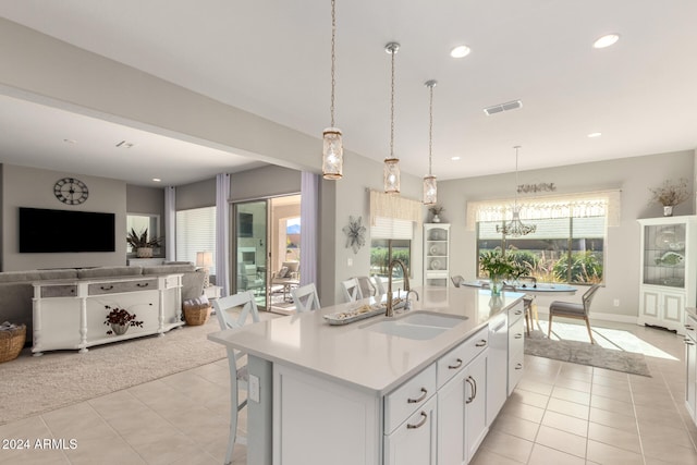 kitchen featuring white cabinetry, sink, light tile patterned floors, and an island with sink