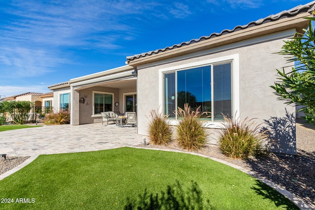 back of property with a yard and a patio