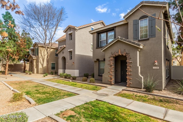 view of front of property featuring a tile roof, fence, and stucco siding