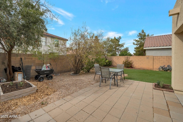 view of patio / terrace featuring outdoor dining space, a garden, and a fenced backyard